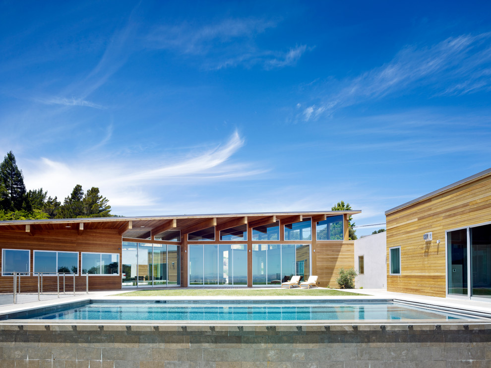 Bild på en mycket stor funkis rektangulär pool, med poolhus och betongplatta
