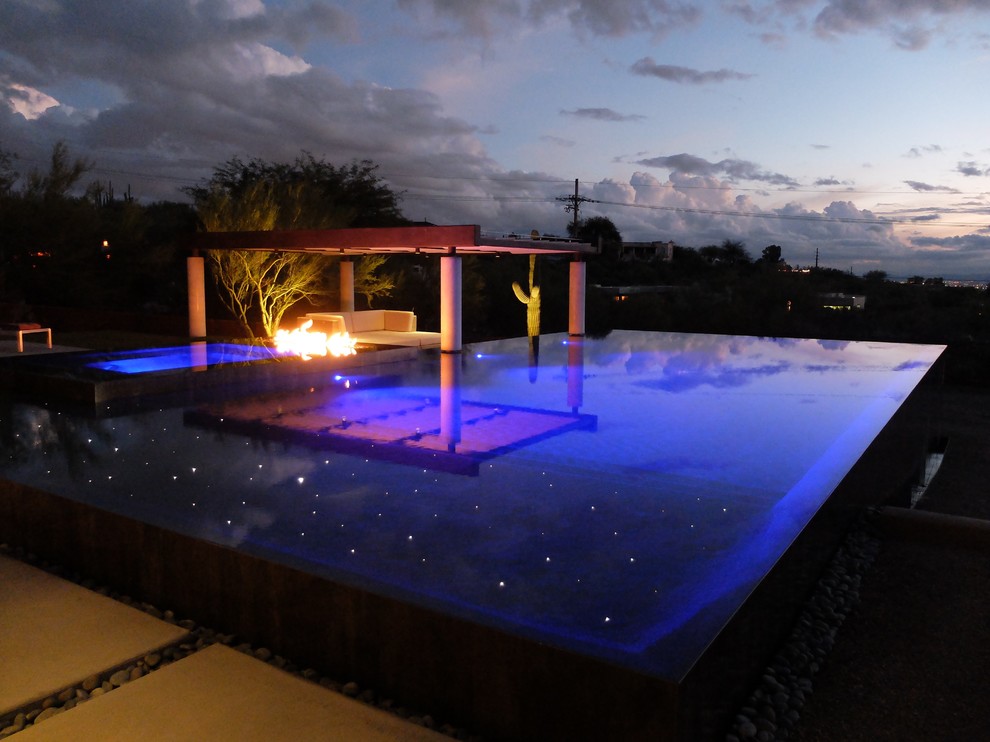 Modelo de piscinas y jacuzzis infinitos contemporáneos grandes rectangulares en patio trasero con adoquines de hormigón