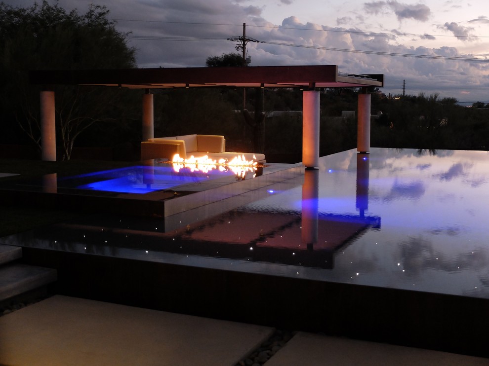 Esempio di una grande piscina a sfioro infinito design rettangolare dietro casa con una vasca idromassaggio e pavimentazioni in cemento