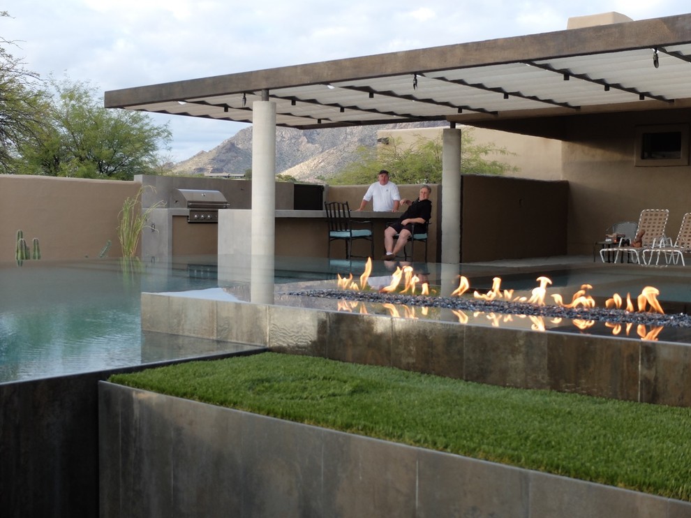 Immagine di una grande piscina a sfioro infinito design rettangolare dietro casa con una vasca idromassaggio e pavimentazioni in cemento