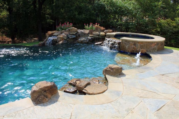 Inspiration for a mid-sized contemporary backyard stone and custom-shaped infinity pool fountain remodel in Austin