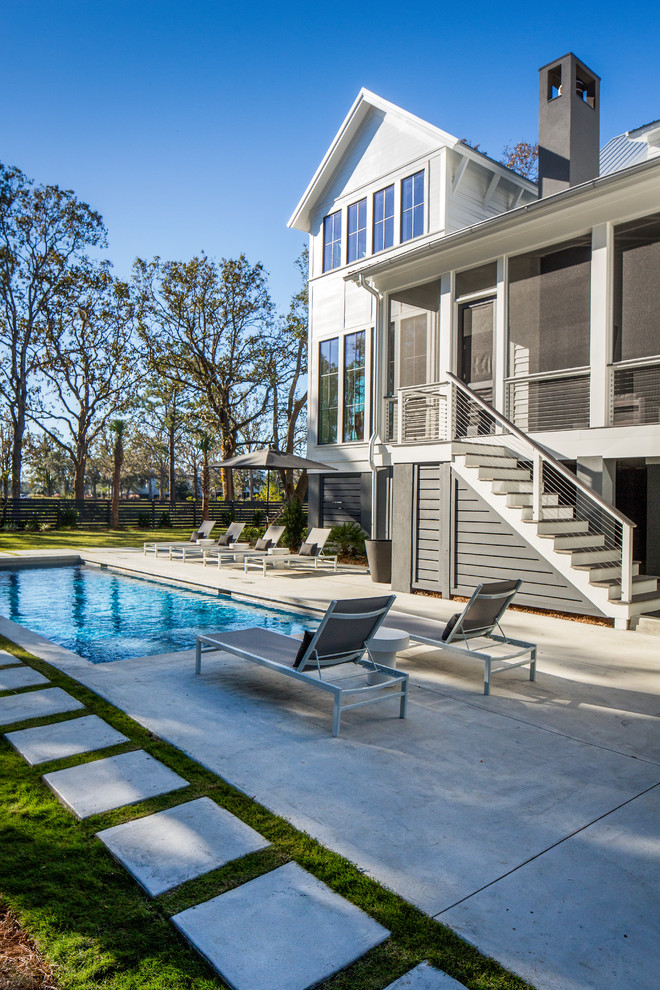 Réalisation d'un grand Abris de piscine et pool houses arrière design rectangle avec des pavés en béton.