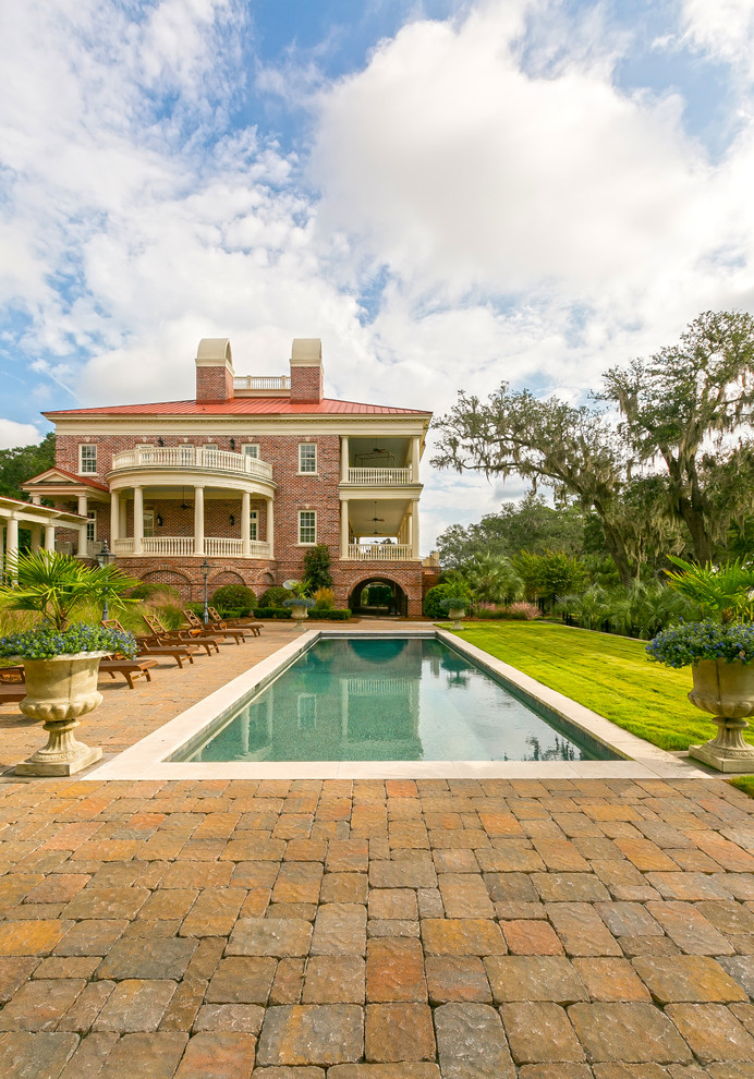 Imagen de casa de la piscina y piscina alargada clásica grande rectangular en patio trasero con adoquines de hormigón
