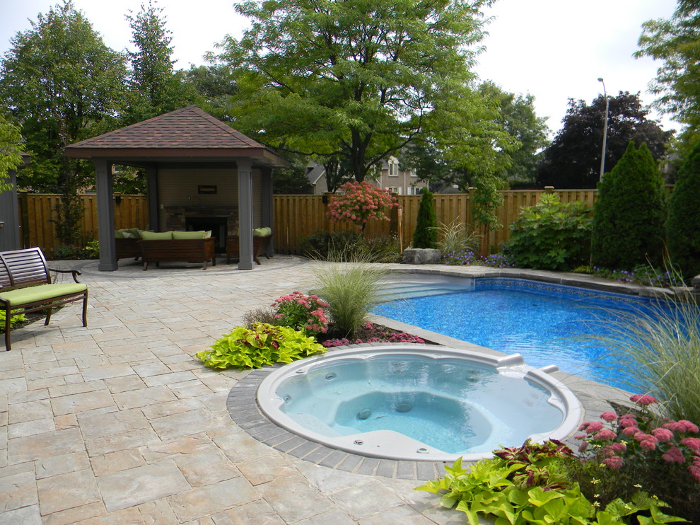 Ispirazione per una piscina classica rettangolare di medie dimensioni e dietro casa con una vasca idromassaggio e pavimentazioni in cemento