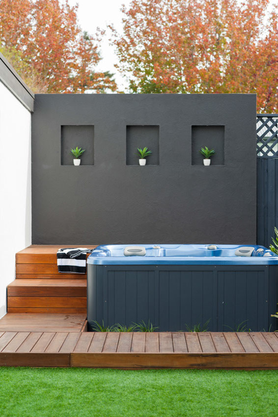 Exemple d'une grande piscine arrière exotique avec un bain bouillonnant et une terrasse en bois.