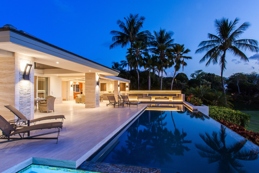 Immagine di una piscina a sfioro infinito design personalizzata dietro casa e di medie dimensioni con piastrelle e una vasca idromassaggio
