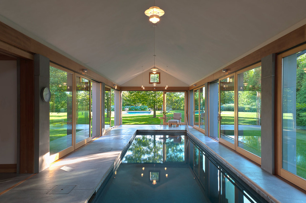 Diseño de piscina alargada contemporánea grande interior y rectangular con losas de hormigón