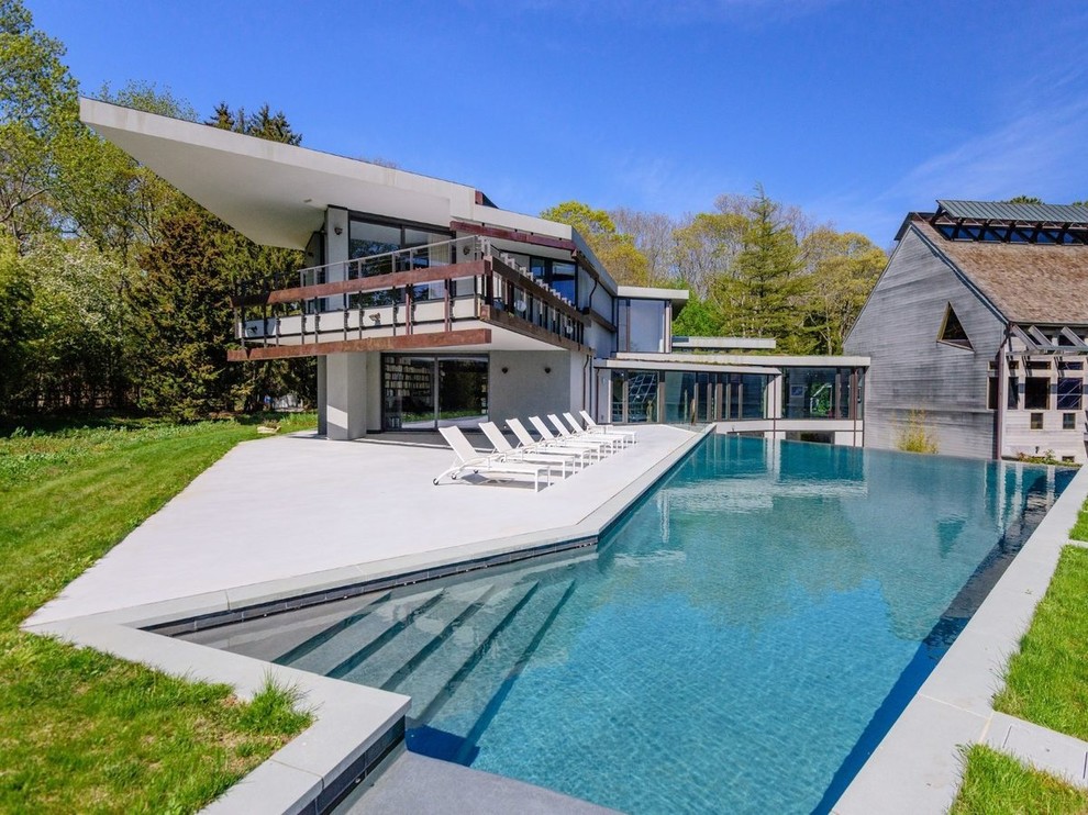 Example of a large trendy backyard concrete and custom-shaped infinity pool design in Other