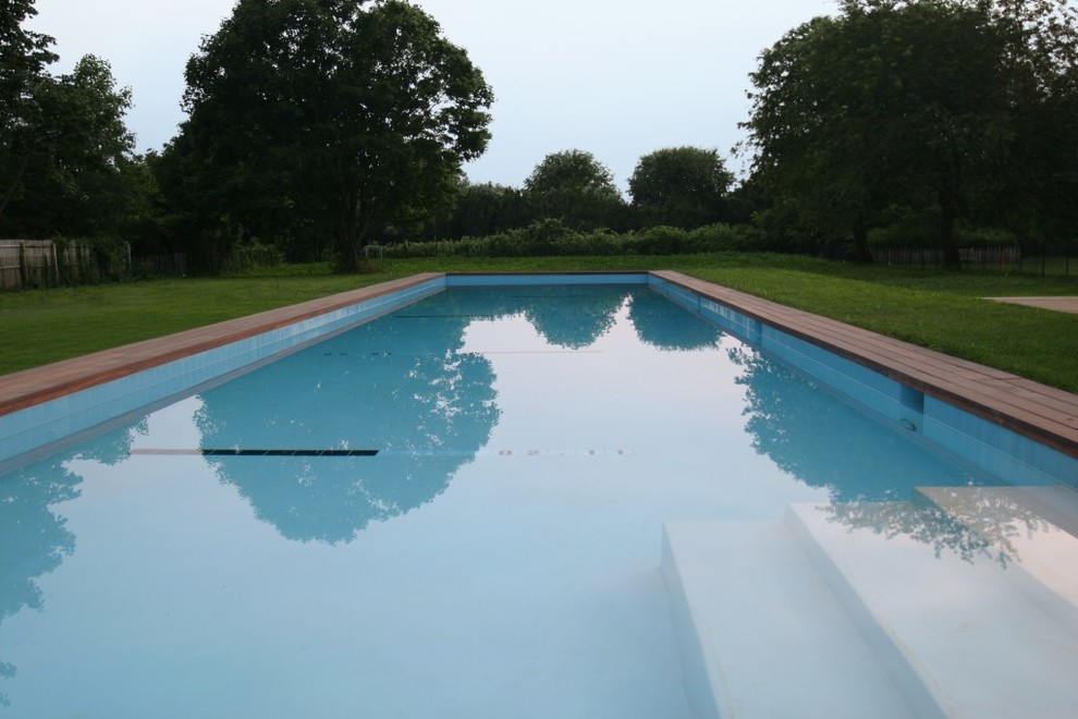 Design ideas for a large modern back rectangular lengths swimming pool in New York with a pool house and decking.