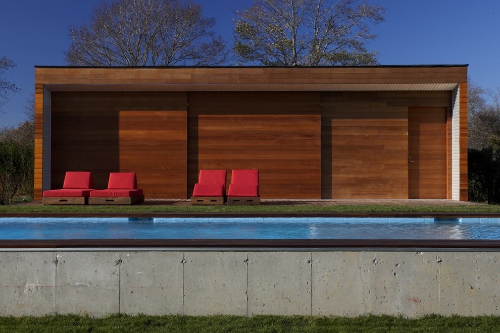Inspiration för stora moderna rektangulär träningspooler på baksidan av huset, med poolhus och trädäck