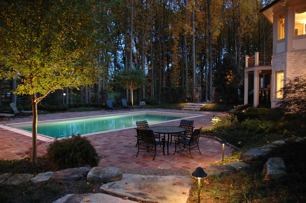 Diseño de piscina alargada tradicional de tamaño medio rectangular en patio trasero con adoquines de ladrillo