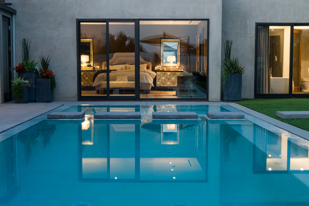 Design ideas for a large contemporary back rectangular lengths swimming pool in Los Angeles with a pool house and tiled flooring.