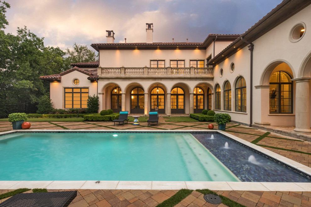Diseño de piscina mediterránea grande rectangular en patio trasero con paisajismo de piscina y adoquines de piedra natural