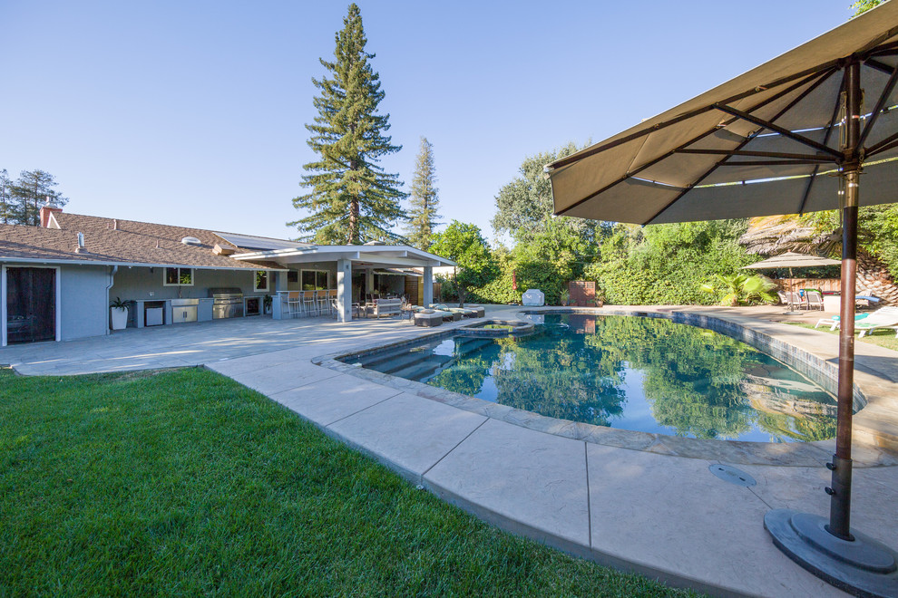 Exempel på en stor klassisk rund pool på baksidan av huset, med spabad och naturstensplattor