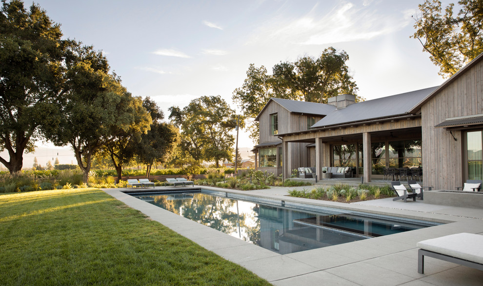 Esempio di una piscina country rettangolare dietro casa con una vasca idromassaggio e lastre di cemento