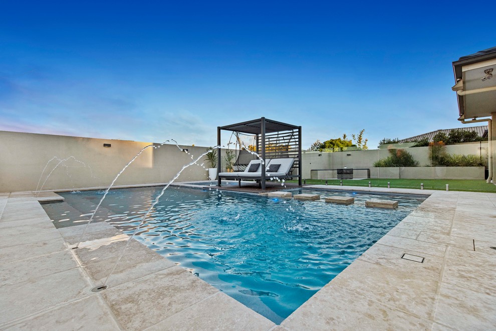 Imagen de piscina con fuente natural mediterránea rectangular en patio trasero con adoquines de piedra natural