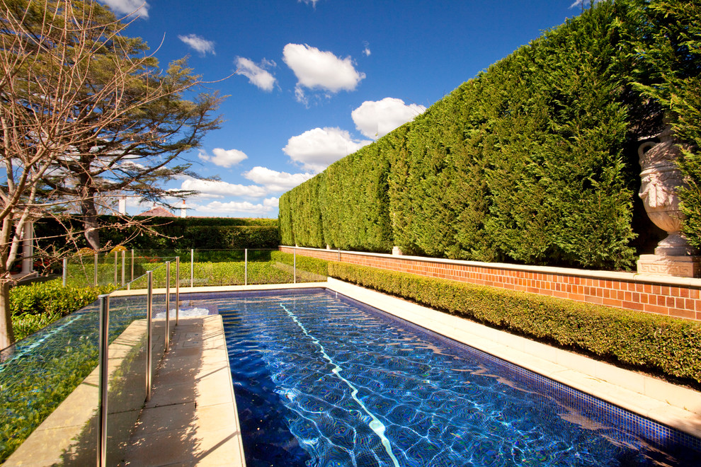 Großer Klassischer Pool hinter dem Haus in L-Form mit Natursteinplatten in Sydney