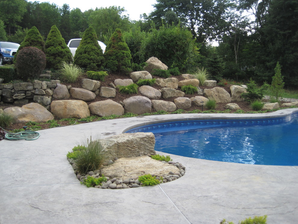 Inspiration för en stor vintage anpassad pool på baksidan av huset, med betongplatta