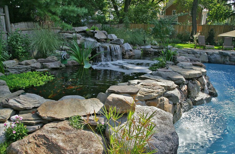 Пример оригинального дизайна: естественный бассейн среднего размера, произвольной формы на заднем дворе в стиле кантри с покрытием из каменной брусчатки