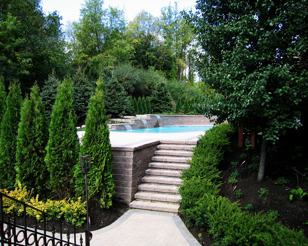 Ispirazione per una grande piscina a "C" dietro casa con fontane e pavimentazioni in mattoni