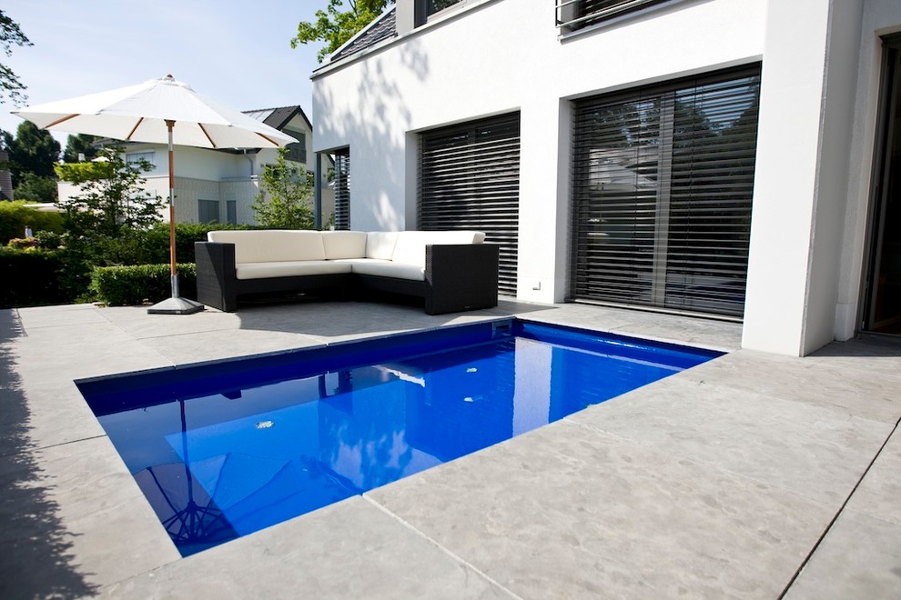 Immagine di una piccola piscina monocorsia classica rettangolare nel cortile laterale con lastre di cemento