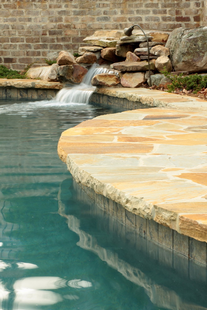Ispirazione per una piscina monocorsia american style personalizzata di medie dimensioni e dietro casa con fontane e pavimentazioni in pietra naturale