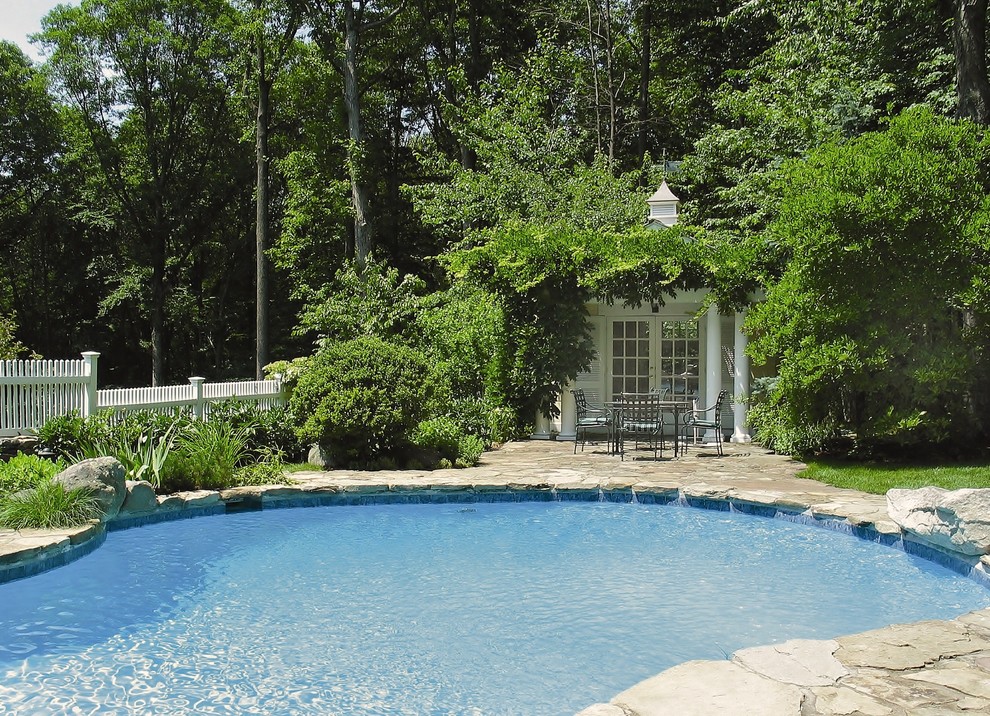 На фото: большой естественный бассейн в форме фасоли на заднем дворе в классическом стиле с домиком у бассейна и покрытием из каменной брусчатки