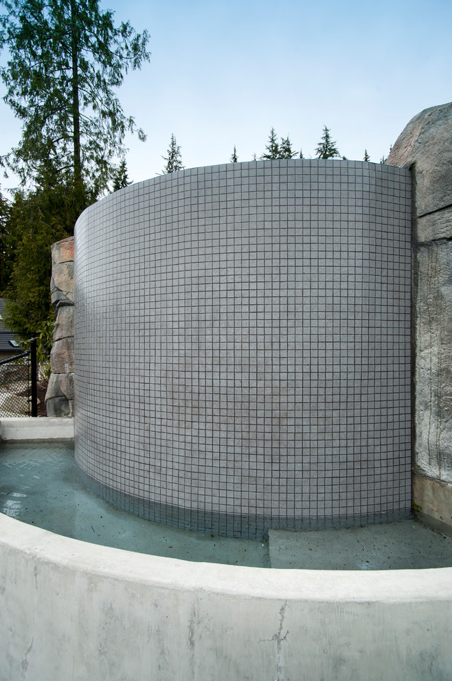 Modelo de piscina con fuente infinita contemporánea a medida en patio trasero con losas de hormigón