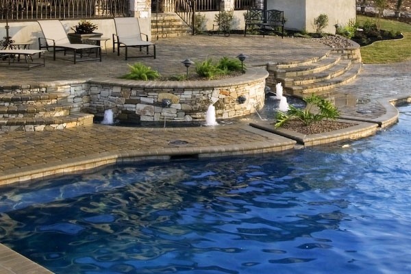 Imagen de piscina con fuente infinita moderna de tamaño medio rectangular en patio trasero con adoquines de piedra natural