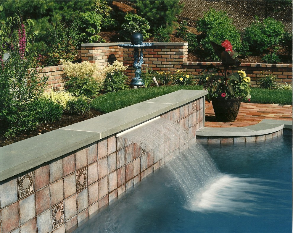 Mid-sized elegant backyard brick and custom-shaped lap pool fountain photo in New York