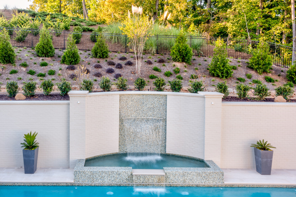 Esempio di una piscina contemporanea personalizzata di medie dimensioni e dietro casa con un acquascivolo e pavimentazioni in pietra naturale