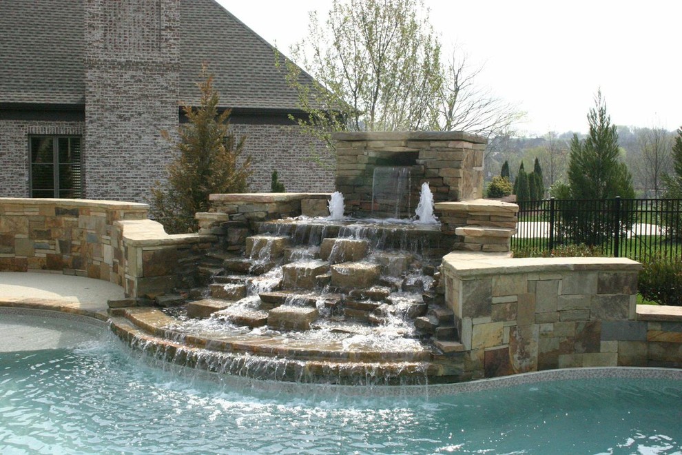 Modelo de piscina con fuente rural grande a medida en patio trasero con losas de hormigón