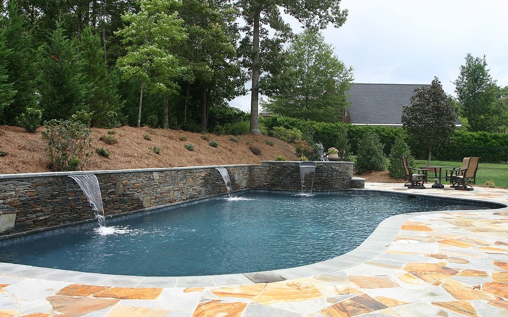 На фото: большой спортивный бассейн произвольной формы на заднем дворе в стиле неоклассика (современная классика) с фонтаном и покрытием из каменной брусчатки