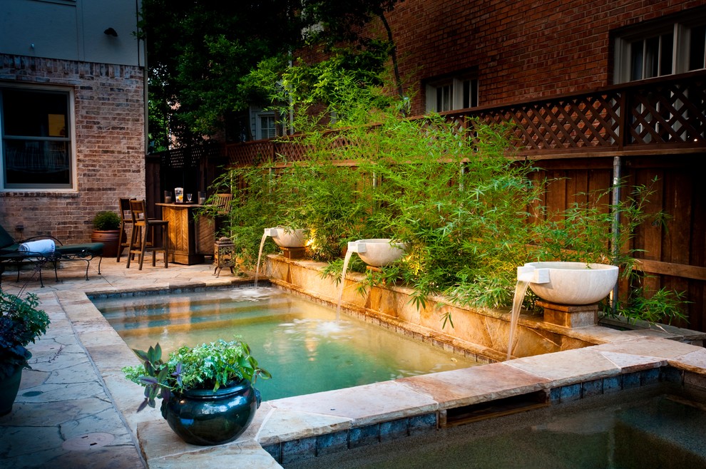Réalisation d'une petite piscine arrière tradition rectangle avec des pavés en pierre naturelle et un bain bouillonnant.