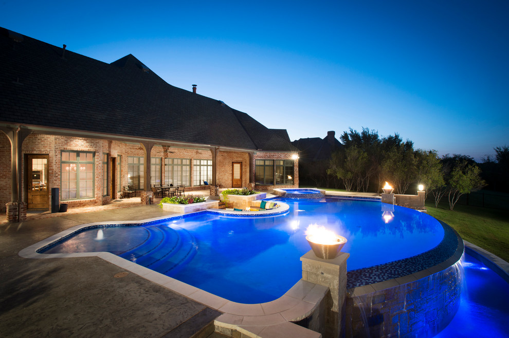Diseño de piscina con fuente infinita tradicional grande a medida en patio trasero con losas de hormigón