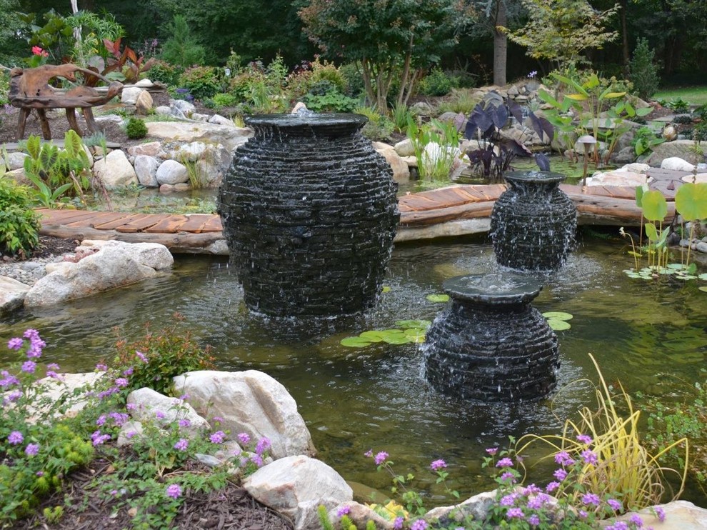 This is an example of a large traditional back full sun garden in Orange County with a pond and mulch.