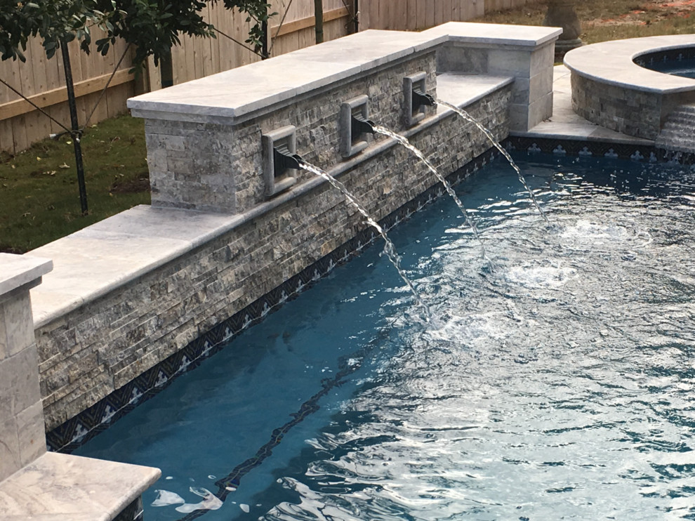 Medium sized back rectangular lengths swimming pool in Houston with a water feature and natural stone paving.