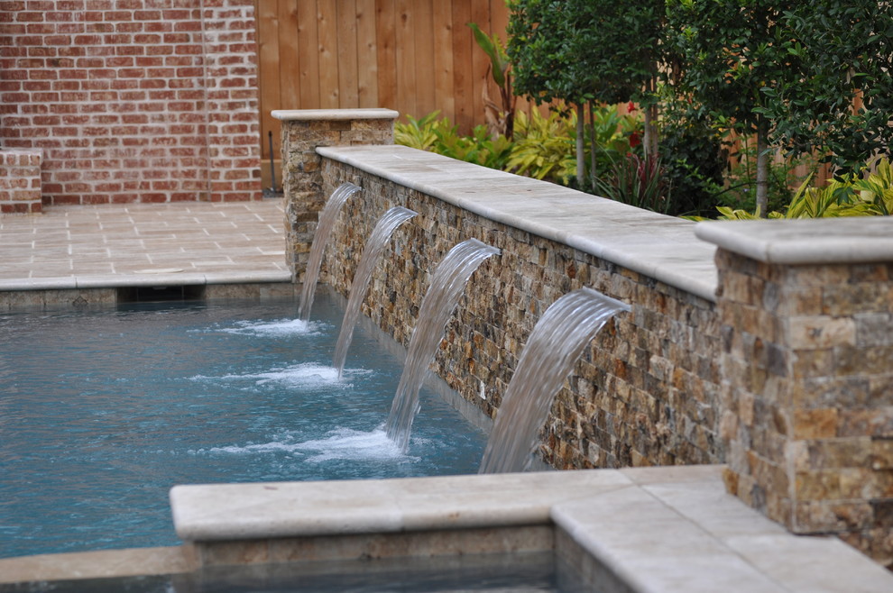 Foto de piscina con fuente alargada clásica renovada de tamaño medio rectangular en patio trasero con adoquines de hormigón