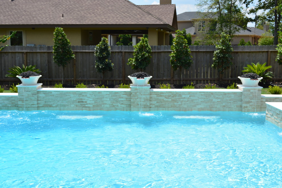 Foto de piscina con fuente alargada minimalista grande a medida en patio trasero con adoquines de piedra natural