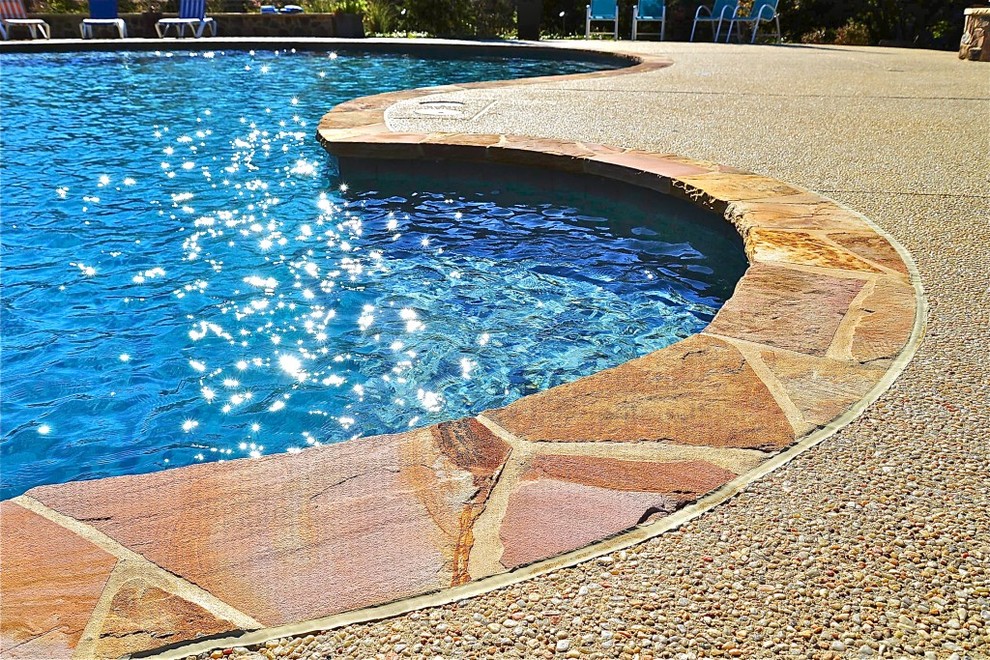 Exempel på en stor modern anpassad pool på baksidan av huset, med vattenrutschkana och naturstensplattor