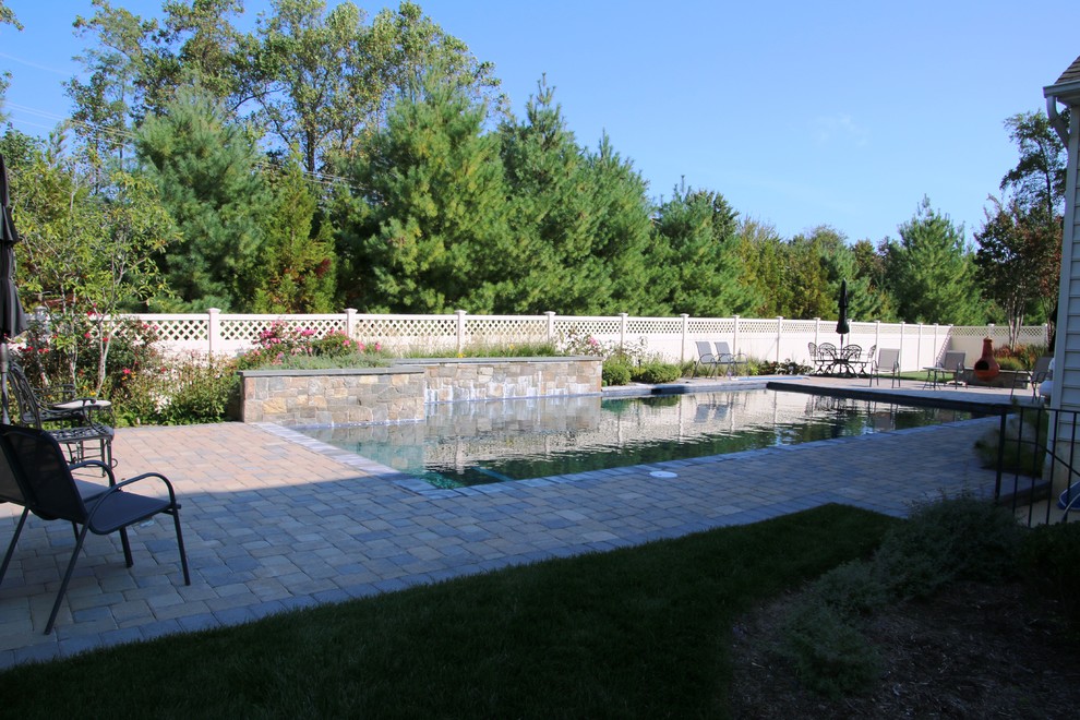 This is an example of a medium sized classic back rectangular swimming pool in Baltimore with a water feature and brick paving.