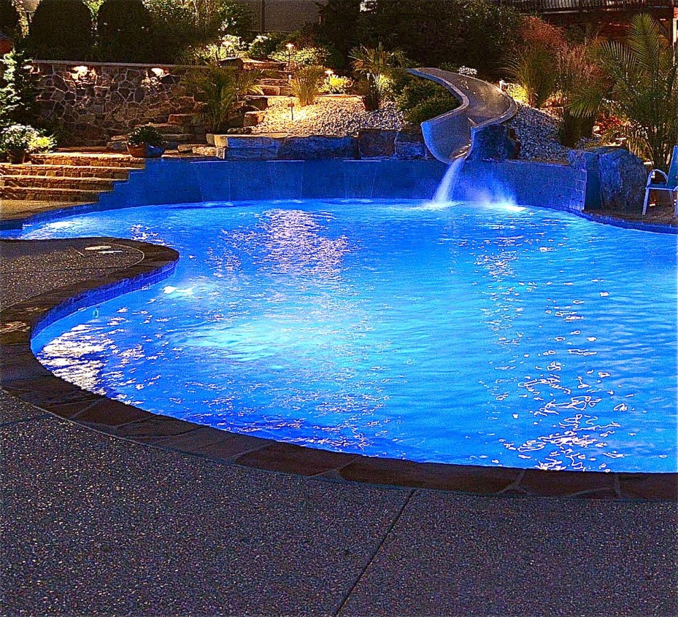 Foto di una grande piscina minimal personalizzata dietro casa con un acquascivolo e pavimentazioni in pietra naturale
