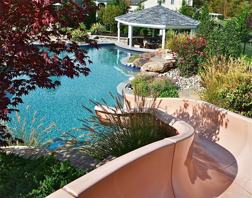 Idee per una grande piscina minimal personalizzata dietro casa con un acquascivolo e pavimentazioni in pietra naturale