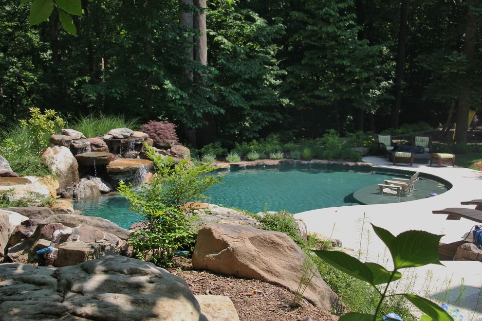 Diseño de piscina con fuente grande a medida en patio trasero con adoquines de piedra natural