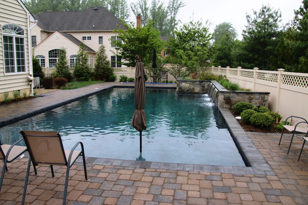 Medium sized classic back rectangular swimming pool in Baltimore with a water feature and brick paving.