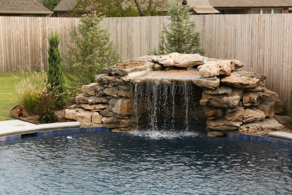 Esempio di una grande piscina monocorsia stile americano personalizzata dietro casa con fontane e lastre di cemento