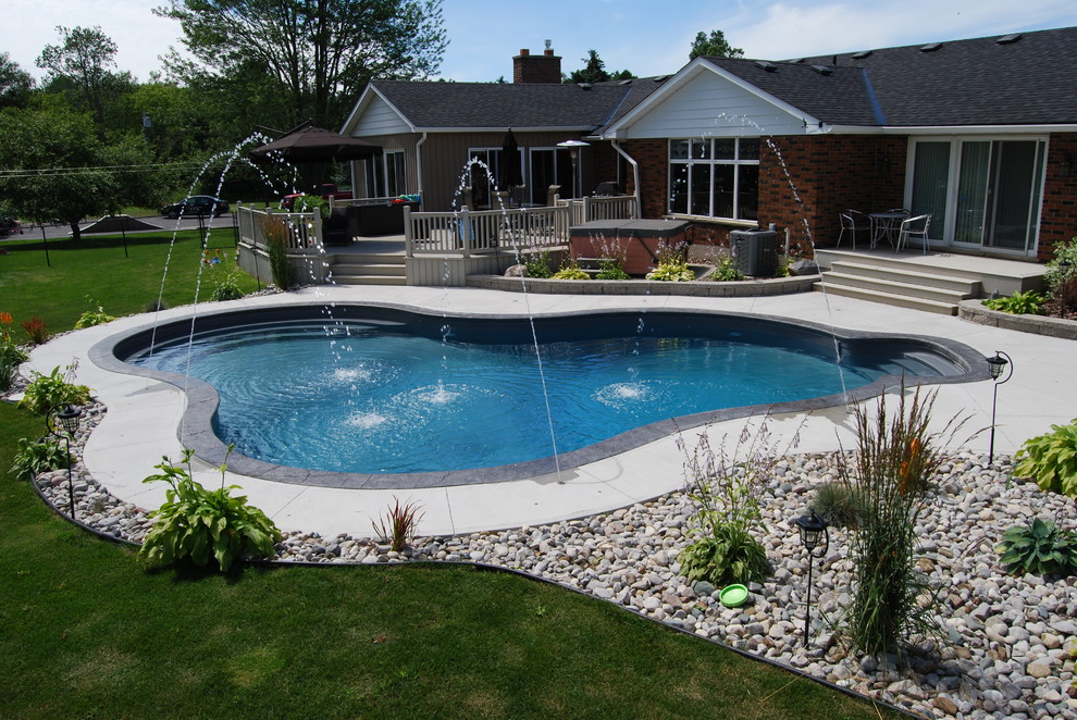 Foto di una grande piscina tradizionale personalizzata dietro casa con fontane e lastre di cemento