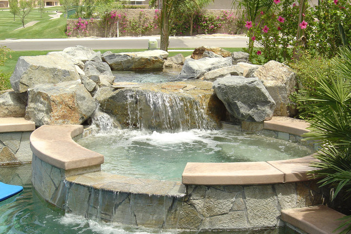 Modelo de piscinas y jacuzzis mediterráneos pequeños redondeados en patio trasero con adoquines de piedra natural