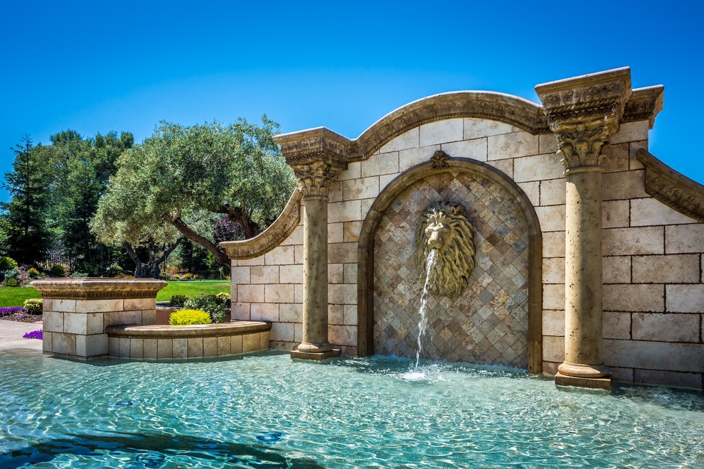 Großer Mediterraner Schwimmteich hinter dem Haus in rechteckiger Form mit Wasserspiel und Natursteinplatten in Dallas