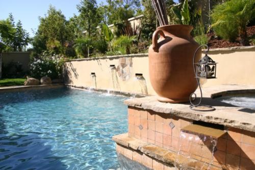Imagen de piscina con fuente elevada mediterránea de tamaño medio rectangular en patio trasero con adoquines de piedra natural